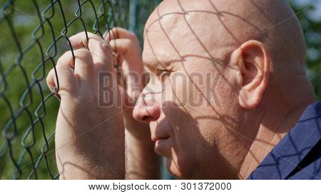 Disillusioned Man Image Looking Sad Thru A Metallic Fence