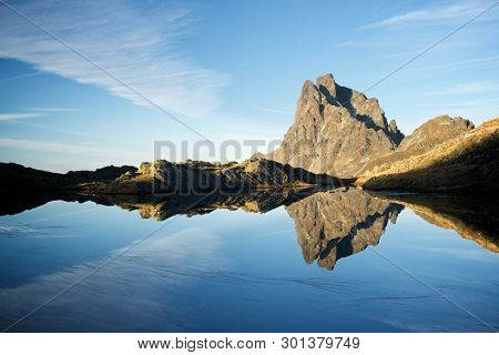 Midi Dossau Peak reflected in a lake. Ossau Valley, Pyrenees National Park, Pyrenees, France.