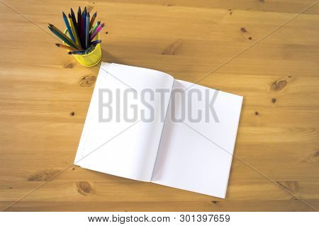 Notebook And Glass With Pencils And Pens On A Wooden Table. View From Above