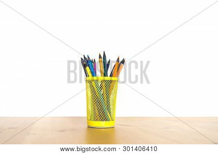 Color Pencils In A Yellow Glass On A Wooden Table On A White Background