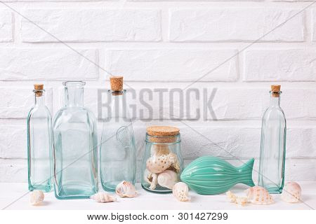 Nautical Or Marine Decorations Near By White Brick Wall. Decorative  Fish, Blue Bottles With Shells.