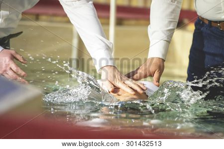 Close Up Of Pastors Hands Who Baptize Man