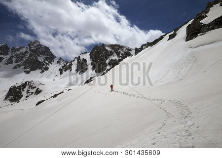 Footpath On Snowy Slope In High Mountains With Avalanche Traces And Hiker In Red With Dog. Turkey, K