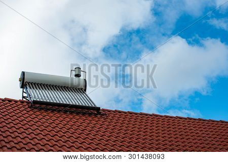 Solar Water Heater Boiler On Residentual House Rooftop, Blue Sky With White Clouds Background, Copy 