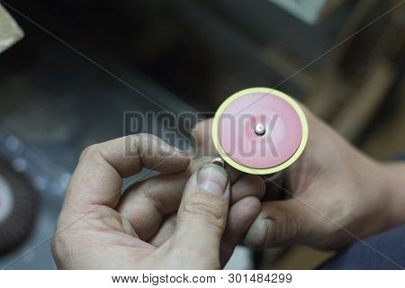 The Master Jeweler Holds The Working Tool In His Hands And Makes Jewelery At His Workplace