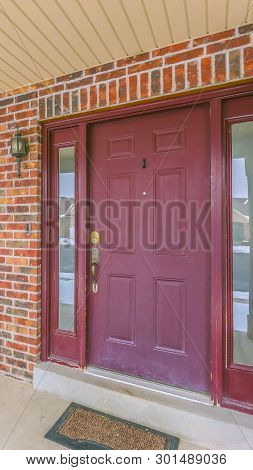 Vertical Facade Of A Home With A Red Front Door And Reflective Sidelights And Windows