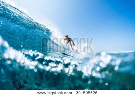 HIMMAFUSHI / MALDIVES - MARCH 08, 2019: Surfer rides tropical, crystal clear ocean wave
