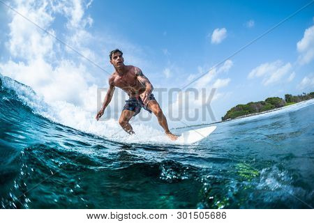 HIMMAFUSHI / MALDIVES - MARCH 10, 2019: Surfer rides the tropical ocean wave