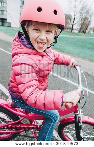 Smiling Caucasian Preschooler Girl Riding Pink Bike Bicycle In Helmet On Backyard Road Outside On Sp