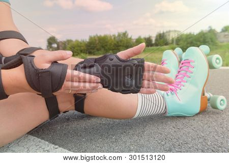 Woman rollerskater wearing wrist guards protector pads on her hand