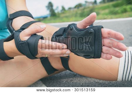 Woman rollerskater wearing wrist guards protector pads on her hand