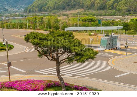 Muju,south Korea; May 1, 2019: Trimmed Evergreen Tree And Purple Azaleas On Corner Of Entrance Gate 