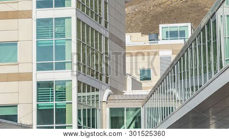 Panorama Sunny Day View Of A Modern Building Exterior With A Glass Walled Skybridge