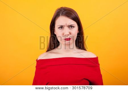 Portrait Of Pensive Young Casual Girl Looking At The Camera Overt Yellow Background