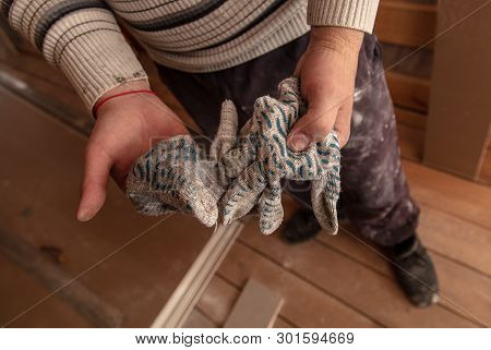 Worker Takes Off Gloves From Hands At A Construction Site.