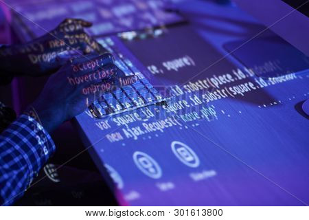 Close-up Of Programmer Sitting At The Table And Working Over New Program Till Night At Office, He Si