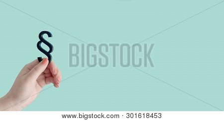 Woman Hand Hold A Paragraph Symbol Of Law And Justice In Front Of Blue Background. Panoramic Image W
