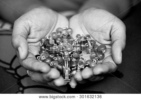 Rosary In Hand In Black And White. Young Junior Lady Holding Rosary With Open Hand With Jesus Christ