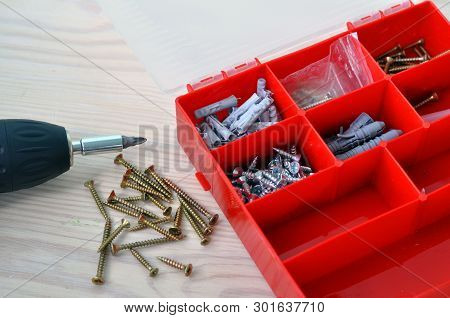 Electric Screwdriver And Screws On A Wooden Table.