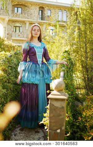 Girl Animator Dressed As A Medieval Princess On The Background Of The Castle In A Beautiful Park