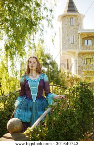 Girl Animator Dressed As A Medieval Princess On The Background Of The Castle In A Beautiful Park