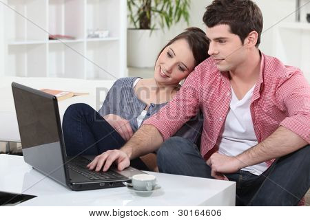 Couple de détente à la maison devant leur ordinateur portable