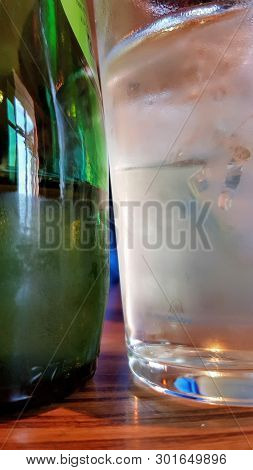 Close Up Of An Ice Cold Green Bottle Of Drink Next To A Frosted Ice Cold Glass
