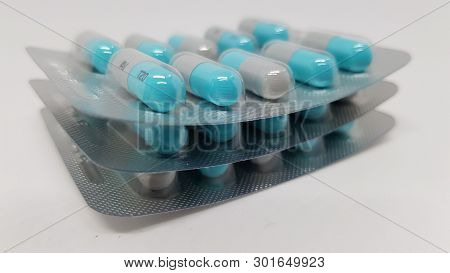 3 Sealed Packets Of Blue And Grey Tablets Stacked On Top Of Each Other.
