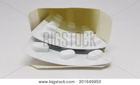2 Strips Of Sealed Tablets Sticking Out Of A Box.