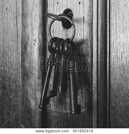 Old Rusty Keys Inside A Keyhole Of An Old Antique Closet. Vintage Design Black And White