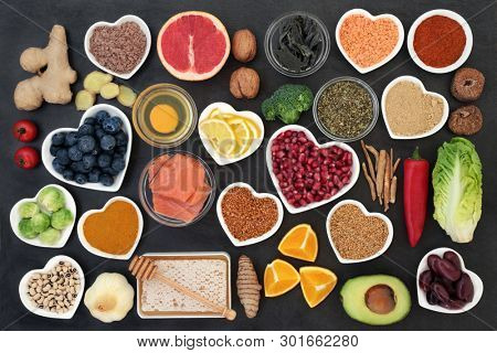 Super food to slow the ageing process concept including fish, fruit, vegetables, herbs, spices, supplement powders honey & dairy on slate. High in antioxidants, anthocyanins, dietary fibre & vitamins.
