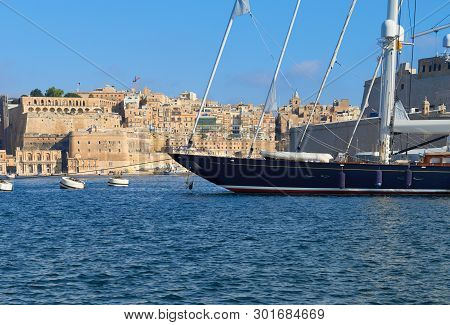 Sailing Ship Moored In Vittoriosa Marina In Grand Valetta Bay. Valetta Traditional Architecture On A