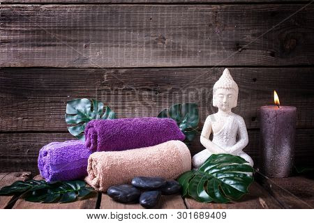 Set Of Towels For Spa, Burning Candle, Black Stones And  Buddha On  Rustic Textured Wooden Backgroun
