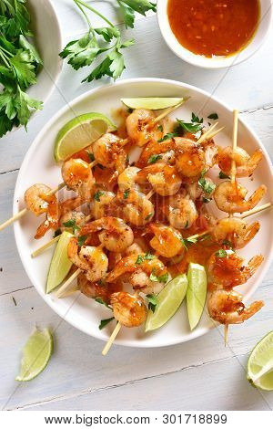 Grilled Shrimp Skewers With Sauce On Plate Over Wooden Table. Tasty Seafood. Top View