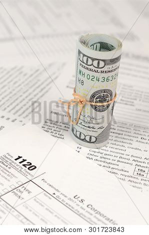 1120 U.s. Corporation Income Tax Return Form With Roll Of American Dollar Banknotes
