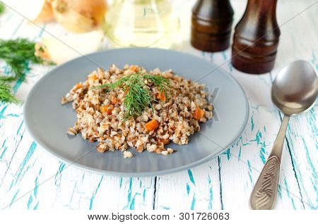 Buckwheat Porridge With Carrots And Parsley In Blue Plate. On Background Of Golden Onions,green Pars
