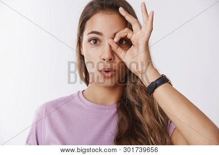 Cute Playful Curious Young Female University Student Showing Circle Okay Gesture On Eye Looking Thro