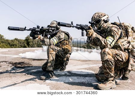 Armed Soldiers With A Rifle In Their Hands Aim At Enemies Sitting On The Roof Of The Building