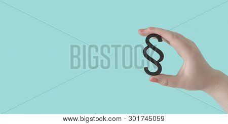 Woman Hand Hold A Paragraph Symbol In Front Of Blue Background. Panoramic Image With Copy Space.