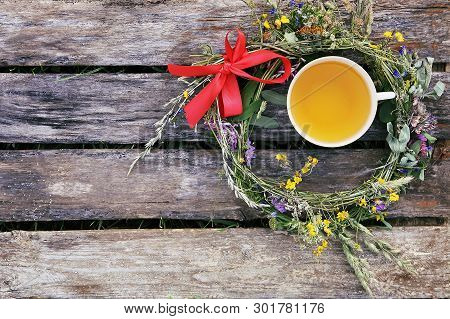 Herbal Tea Of Medical Plants In A Cup On Weathered Wooden Boards Outdoors.