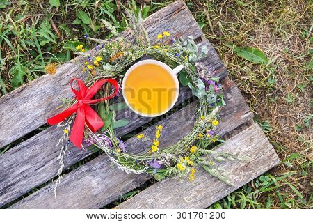 Herbal Tea Of Medical Plants In A Cup On Weathered Wooden Boards Outdoors.
