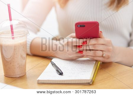 Cropped Image Of Unrecognizable Woman With Red Manicure, Holding Smart Phone In Both Hands, Making N