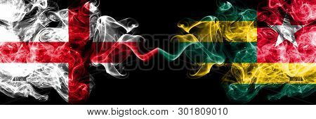 English Vs Togo, Togolese Smoky Mystic Flags Placed Side By Side. Thick Colored Silky Smokes Flag Of