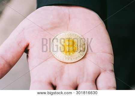 Golden Bitcoin In A Man Hand, Digitall Symbol Of A New Virtual Currency.