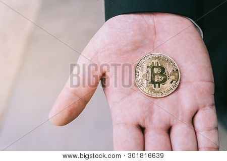 Golden Bitcoin In A Man Hand, Digitall Symbol Of A New Virtual Currency.