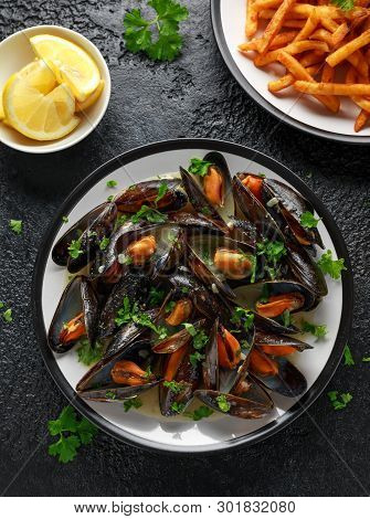 Mussels With White Wine, Garlic, Lemon And Herbs In A Plate, French Fries. Rustick Background. Seafo