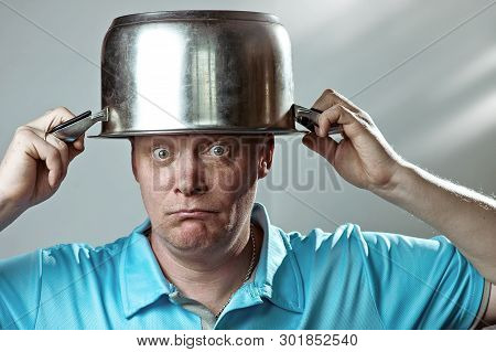 A Bald Brutal Man In A Blue T-shirt Put A Pot On His Head