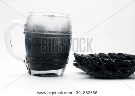 Raw Organic Bitter Melon Or Bitter Gourd With Its Extracted Juice In A Transparent Glass With Some I