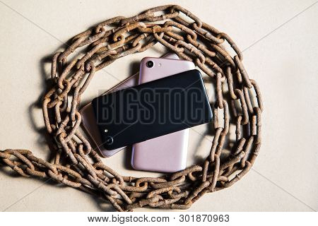 Smartphons In Chains. Old Rusty Chains. Black And Pinc Smartphons