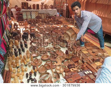 Morjim, India, November 23, 2013. In The Market, An Indian Man Shows And Offers To Buy A Wooden Plat